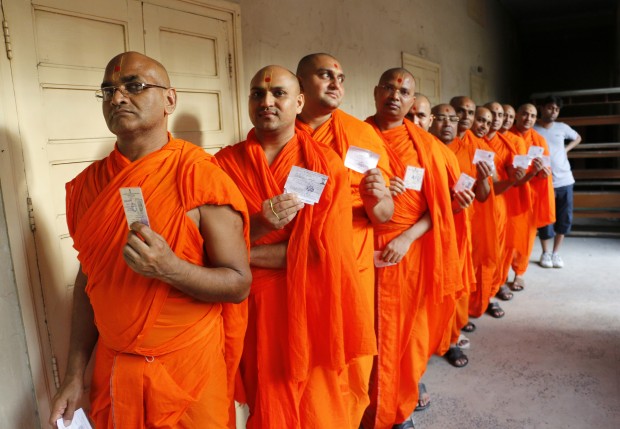 Hindu saints stand in line to cast their votes at a polling station in Ahmedabad